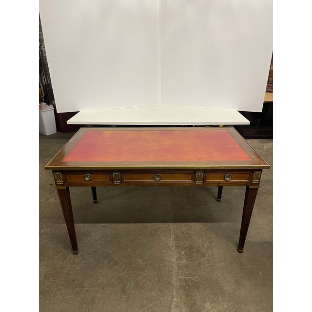 writing desk with a rectangular top inset with a red-orange tooled leather writing surface, brass gallery edge, three...