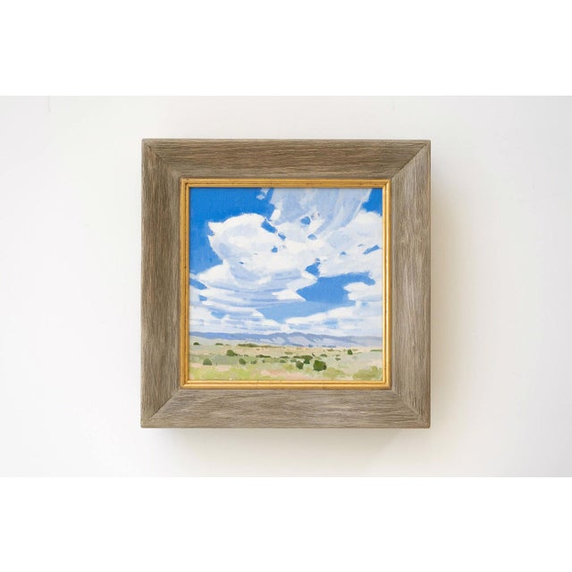 This oil painting captures a serene landscape under a vast sky filled with soft, billowing clouds. The gentle brushwork...
