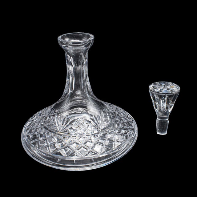 This is a vintage ships decanter and glass duo. An English, cut crystal glass wide bodied brandy or rum bottle with...