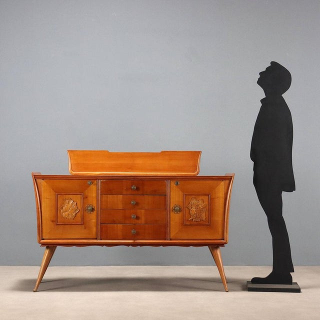 Buffet with a raised top, hinged doors, and exposed central drawers. Maple veneer, carved floral decorations on the doors....