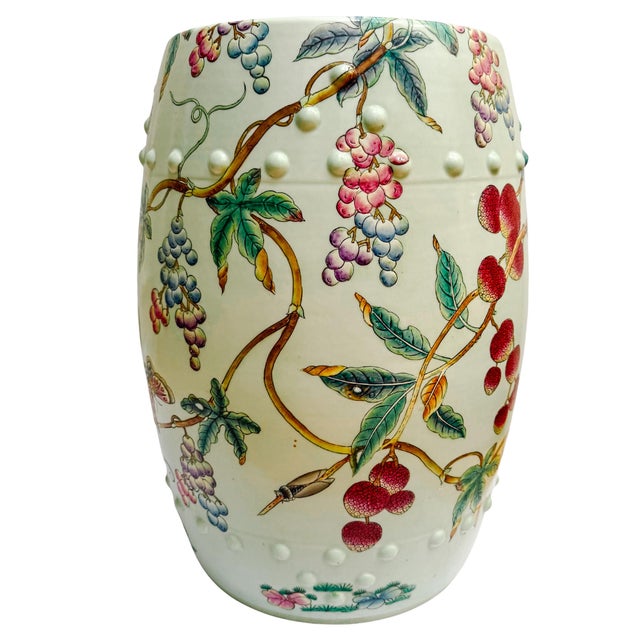 A vibrant vintage Famille Rose porcelain garden stool featuring a lush, hand-painted botanical scene of ripening lychees...
