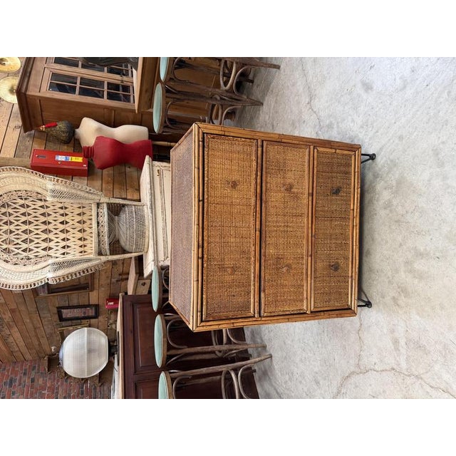 This antique wicker and rattan chest of drawers has been restored and raised on four black metal legs. It has three large,...