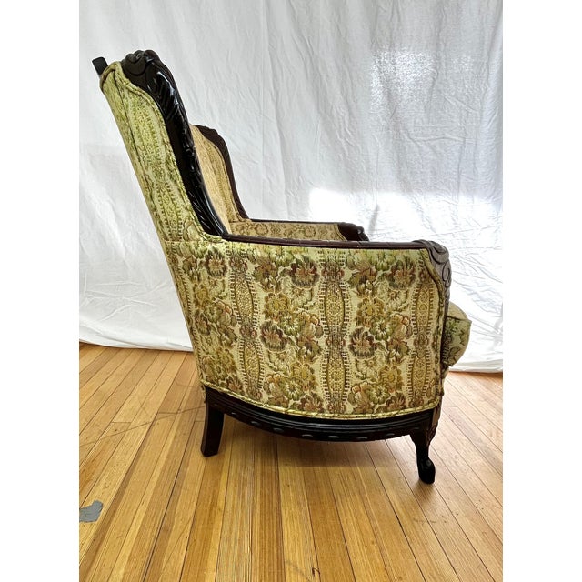 This set of vintage Louis XV Bergère style chairs features beautifully carved walnut frames paired with classic brocade...