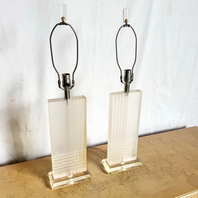 This striking pair of Art Deco lucite table lamps brings sculptural elegance to any space. Each lamp features a tall...