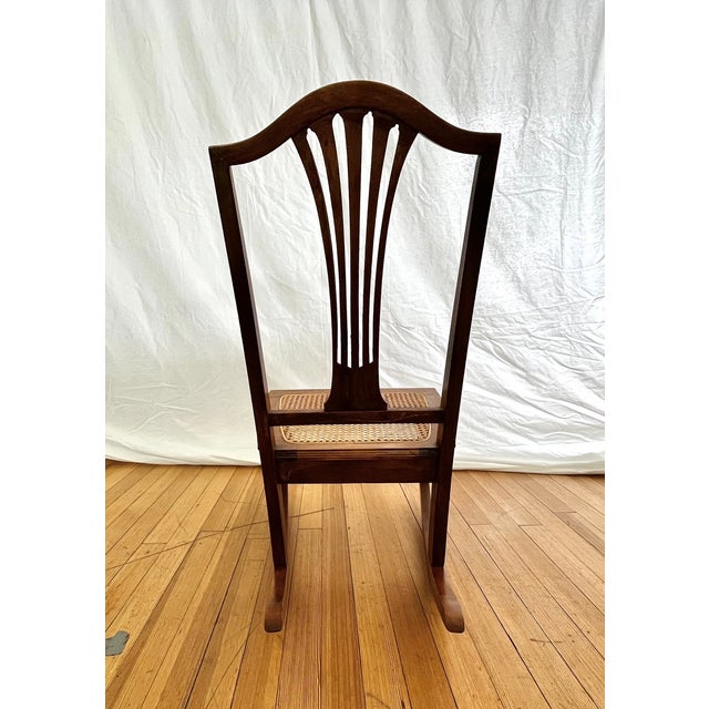 Vintage cane seat rocking chair crafted in the British Colonial / English style, featuring a classic silhouette with...