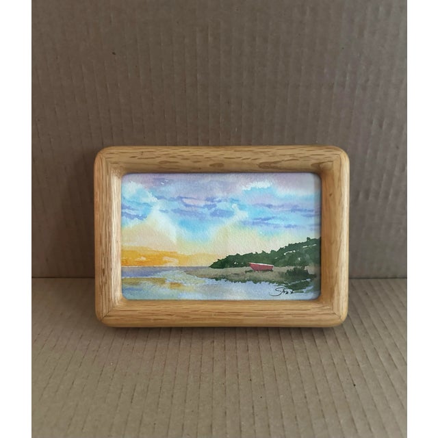 This petite landscape watercolor captures a tranquil coastal scene bathed in the soft glow of sunset. Framed in natural...