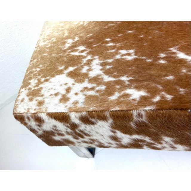 This is a modern natural cowhide bench. This modern bench has sleek square chrome legs with a cream and brown natural...