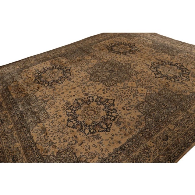 Hand-knotted in wool, this 11x13 antique Persian Tabriz rug features a brown field with black patterns, and gold and...
