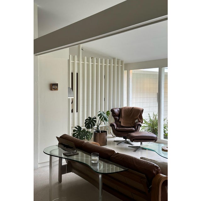 Sculptural vintage console table featuring a freeform glass top resting on a sweeping curved lucite base. The transparent...
