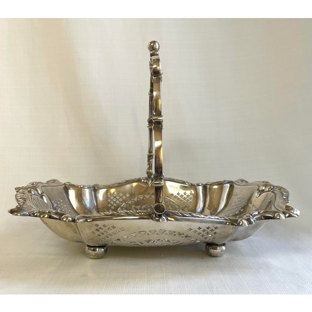 This beautiful ornate silver plate basket features detailed scroll edges with pierced sides. The handle and hinges are...
