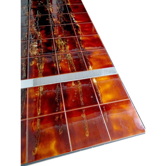 Large mid-century table featuring ceramic tiles supported by a chrome frame. The tiles were produced in flamed hues...