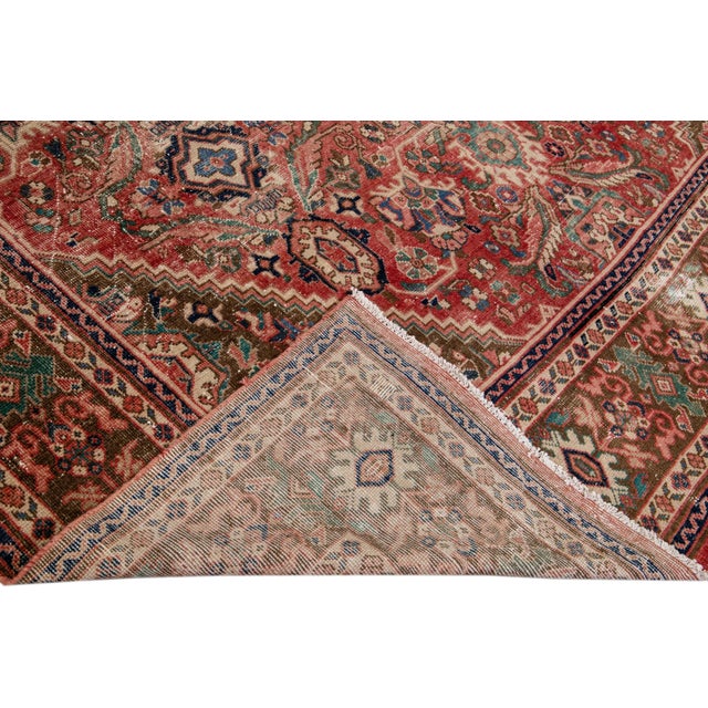 Beautiful vintage Persian distressed hand-knotted wool rug with a red field. This piece has a beige frame and multicolor...