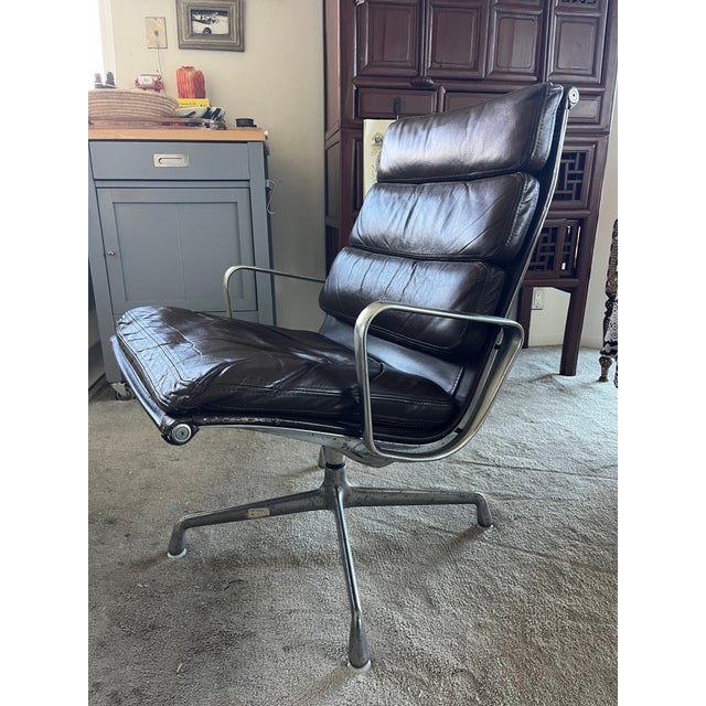 This is a vintage office chair featuring brown leather upholstery divided into multiple padded cushions, set within an...