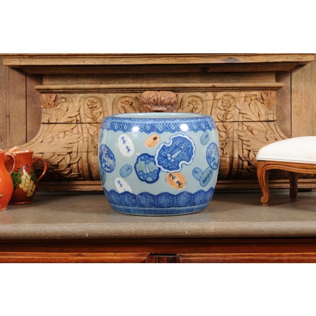 An Asian porcelain cachepot from the late 19th century, with floating cartouches and blue, white and orange tones. Created...