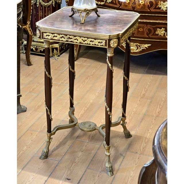 An elegant French Louis XVI style gueridon table featuring a refined square top framed by delicate gilt bronze ormolu...