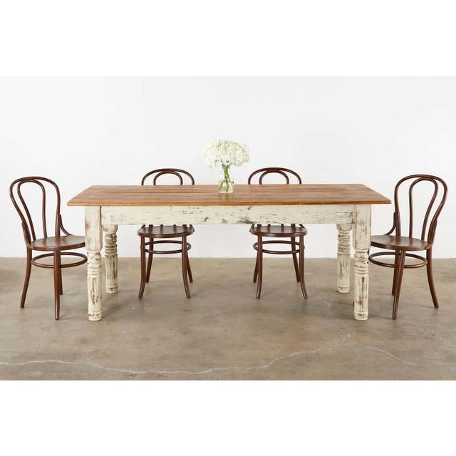 Country American rustic farmhouse dining table or harvest table featuring a cream colored painted pine base. The top is...