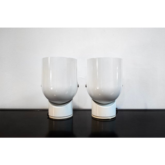 Pair of bedside lamps with painted metal structure, plastic base. Pileino model Designer Gae Aulenti Manufacturer Artemide...