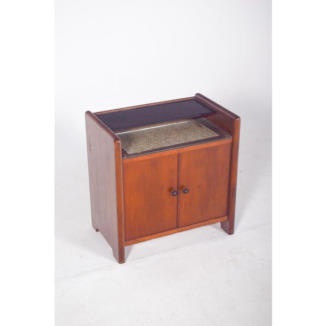 Small bar cabinet with two doors. The upper part has a dark glass top and, just below, a display area also made of glass,...