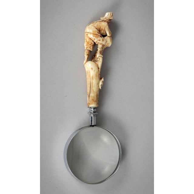 Unusual antique magnifying glass with a hand-carved bone figure atop a tree stump dressed in Austrian lederhosen and...
