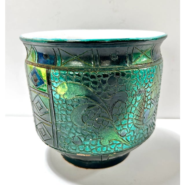 A beautiful vintage raku ceramic planter featuring an intricate peacock motif and richly textured glaze. The deep green...