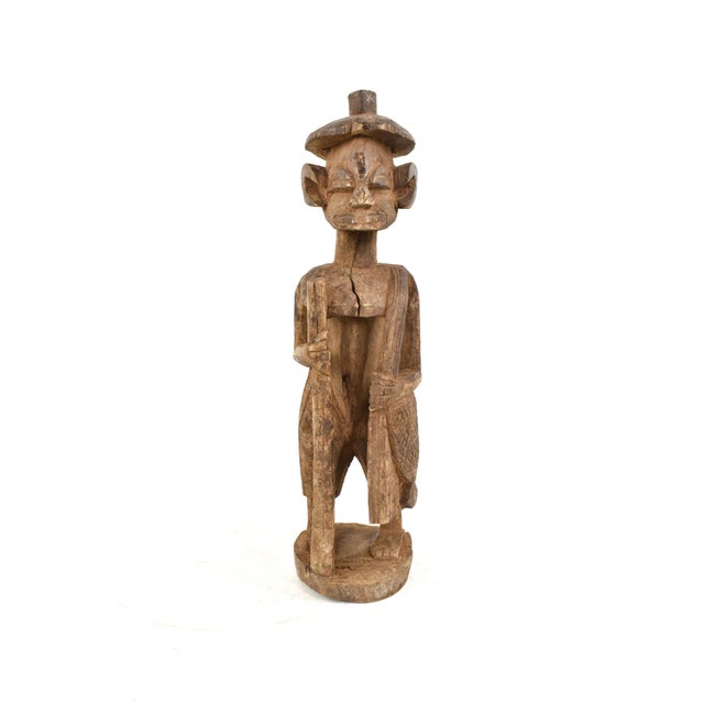 This charming figure sports a walking staff, shoulder bag, and hat. Stands on its own but wobbles a bit. The Senufo people...