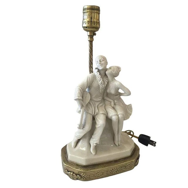 Art Deco era porcelain and brass figurine lamp of a Harlequin girl kissing her minstrel clown. Measure: Base 7" x 4" 13"...