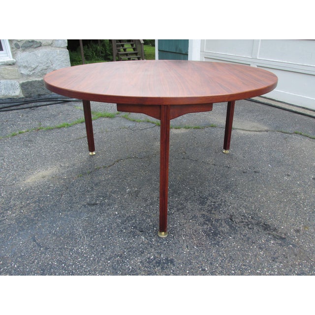 Large (54'' diameter) round dining table by Jens Risom Design, Inc. Walnut. Supported by three legs with adjustable heavy...