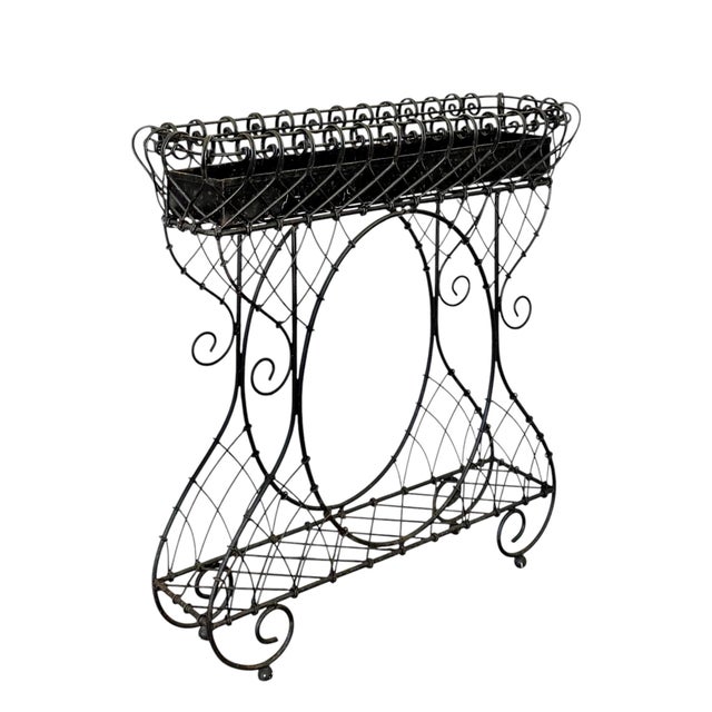 An artful jardinière/planter in iron and iron wire; early 20th century. A lower shelf is fitted within a base composed of...