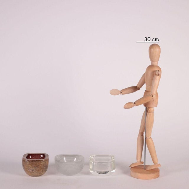 Group of three bowls in different blown glass shape and machining. The bowl in a square shape in colorless glass has a...