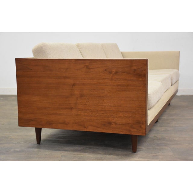 A mid century modern walnut case sofa with beige fabric and tapered legs. Professionally refinished. Seat height is 16”....