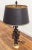 Vintage Mediterranean style wrought iron table lamp with brass toned base. Black 'starter' shade with gold lining.
