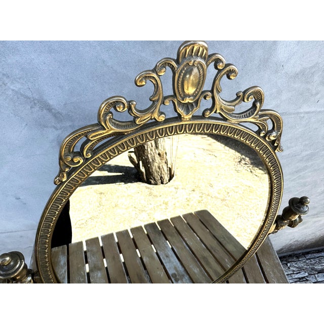 Elegant vintage brass tabletop vanity mirror featuring a richly ornamented Rococo Revival design with strong Hollywood...