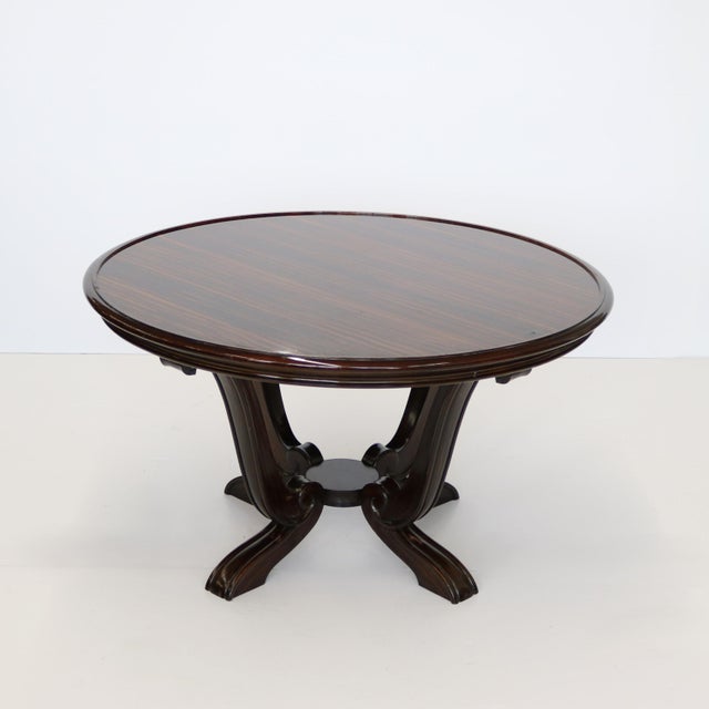 An Art Deco period cocktail table featuring a beautifully veneered recessed top. The tables stands on four heavily carved...