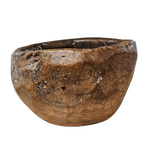 A substantial hand-hewn wooden bowl carved from a single burl section, retaining its irregular form and textured interior....