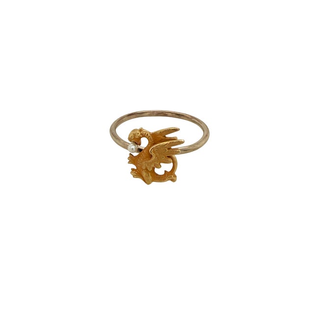 A wonderful 14K gold ring in the form of a griffin holding a seed pearl. Originally a stickpin, a 14K gold shank has been...