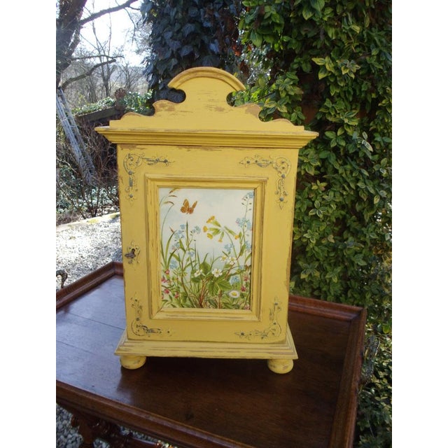 An oak cabinet that evokes summer, sunshine, and good cheer. The cabinet shines in sunny yellow, with metal fittings, an...