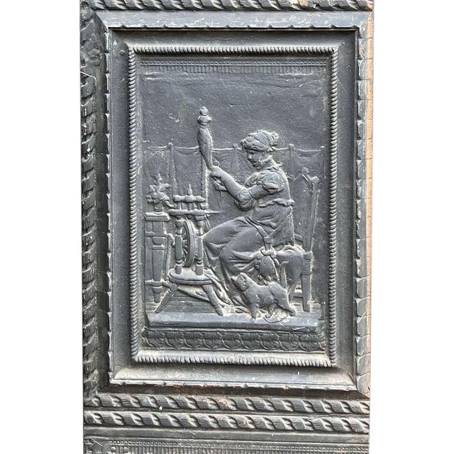 DETAILS An antique side panel from a fireplace hearth fireback with figural scene of a lady with a spinning wheel. An...