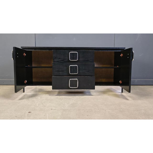 Black wooden cabinet or small sideboard with two doors and three central drawers. Cool handles and an aluminum trim to the...