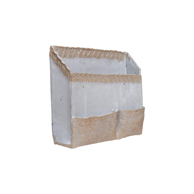 A hand made stoneware letter organizer. The rectangular body is glazed in a milky gray, and unglazed edges are crimped...