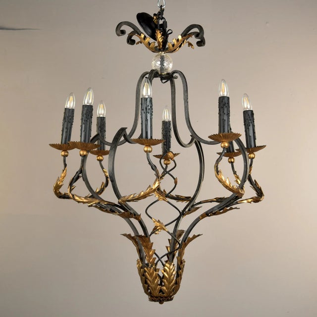 Mid century Italian eight light chandelier has a black iron frame with gilt metal fronds and detailing. Eight candle-style...