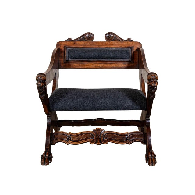 Upholstered arm chair. Carved pediment. Lion head motifs and paw feet.