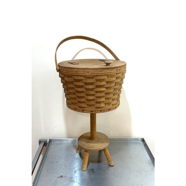 Longaberger classic hinge-top handled sewing basket on wood stand. Some minor surface fading to wicker/wood throughout as...