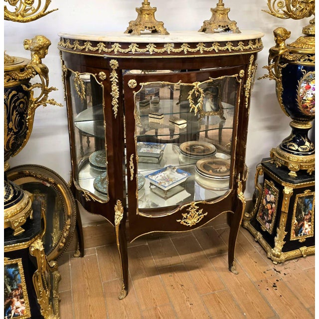 Elegant and richly detailed, this French Louis XV-style display cabinet is crafted from solid wood and designed to...