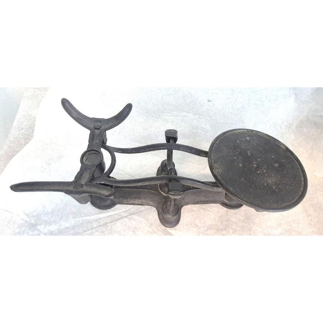This antique cast-iron double-pan balance scale dates roughly from the late 19th century to the early 20th century. It...