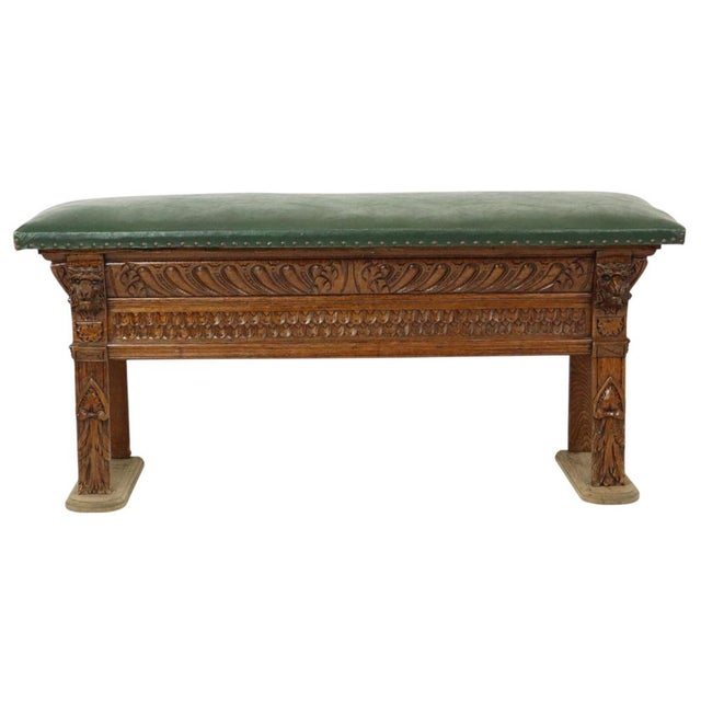 Attractive bench made of carved oak with a green vinyl seat; Renaissance Revival style, first half of the 20th century. A...