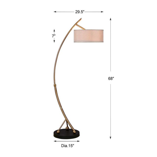 Curved metal finished in a brushed brass accented with a matte black foot. The round hardback drum shade is a beige linen...