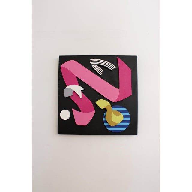 Dimensional wood painting of a celebratory ribbon in bright pink. This upbeat piece features layered pieces of wood upon a...