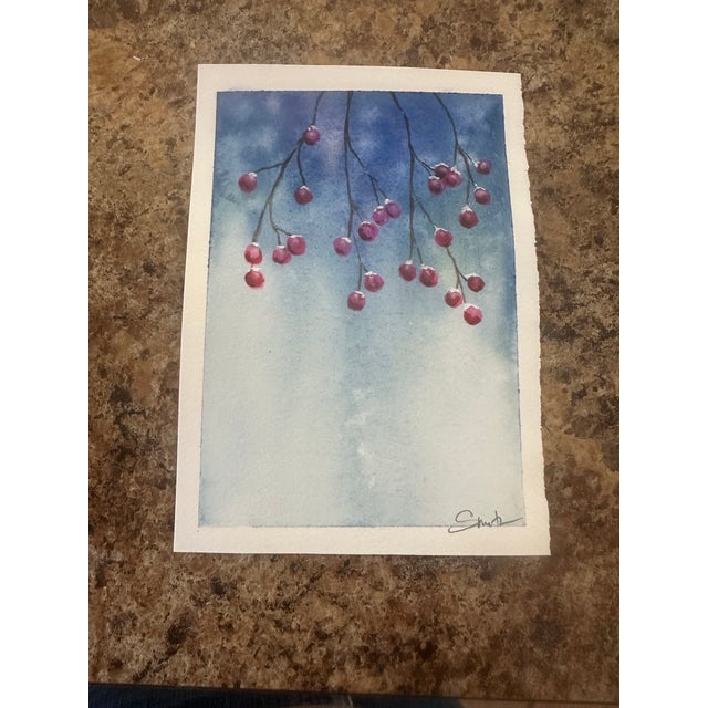 A full arrangement of berry-laden branches drapes across a misty blue background, capturing the quiet abundance of winter....