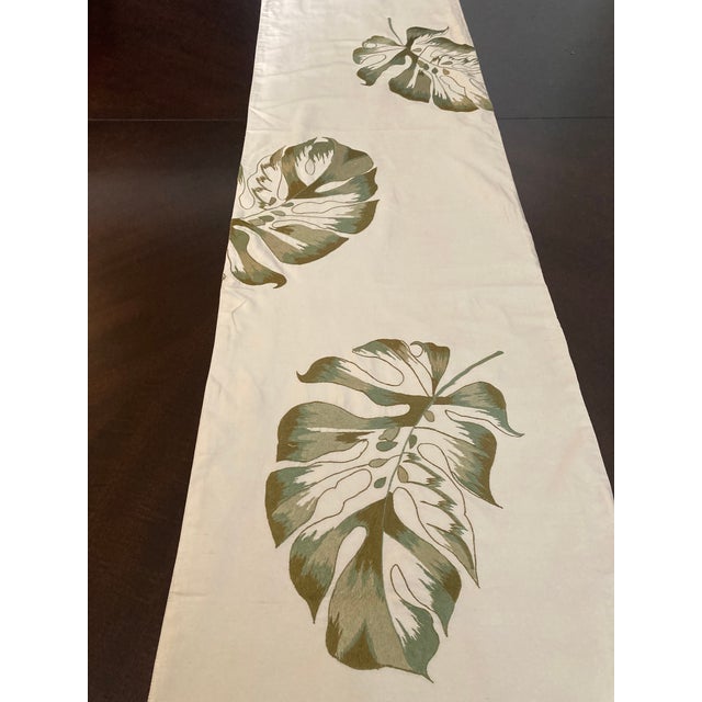 Adorn your dining space with the lush beauty of the Monstera Leaf Motif Embroidered Silk Table Runner from Sethi & Sethi....