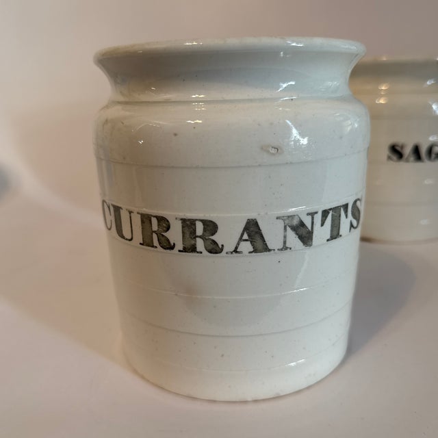 A charming collection of five late 19th-century English ironstone pantry jars, each bearing classic black transfer labels...